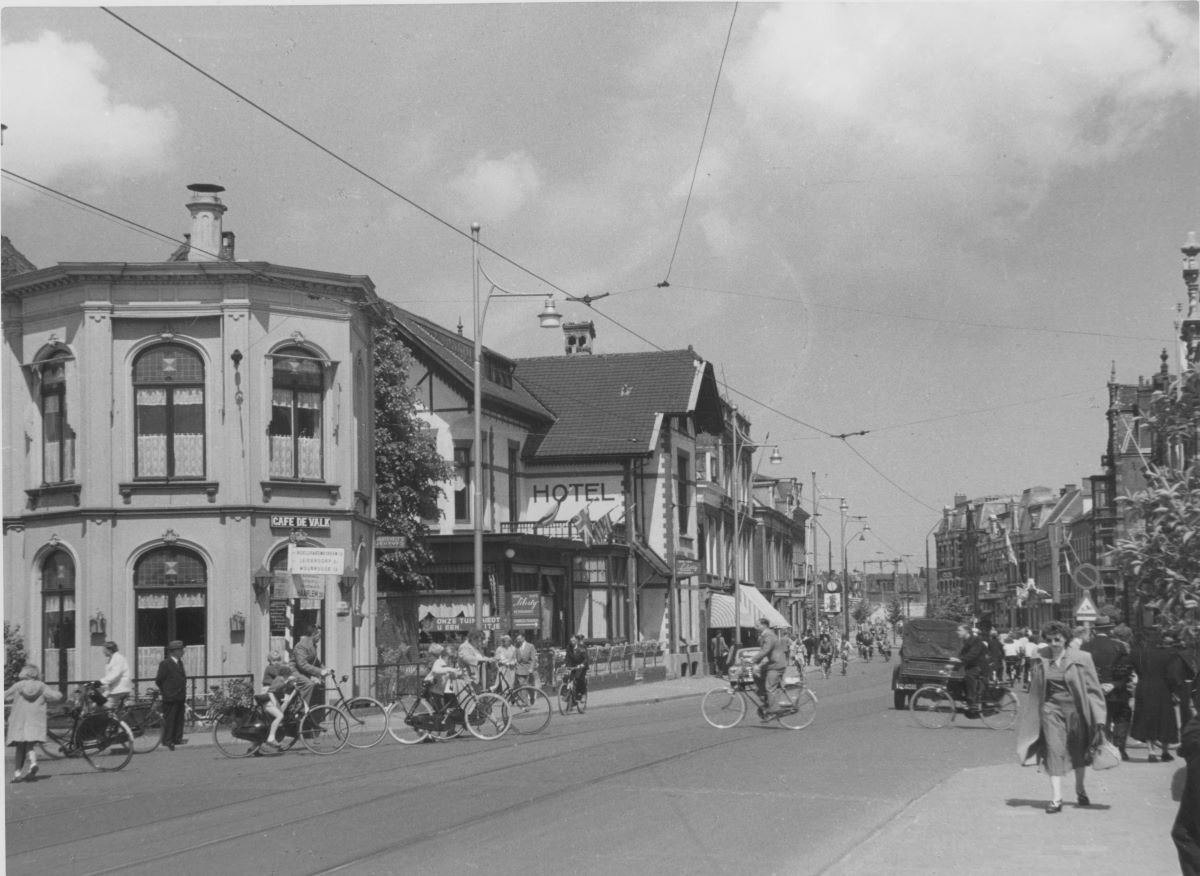 Gezicht in de Stationsweg met links café 'De Valk' en daarachter Liberty. Gezien vanaf de Rijnsburgerbrug bij de Rijnsburgersingel naar het noorden op 7 juni 1954